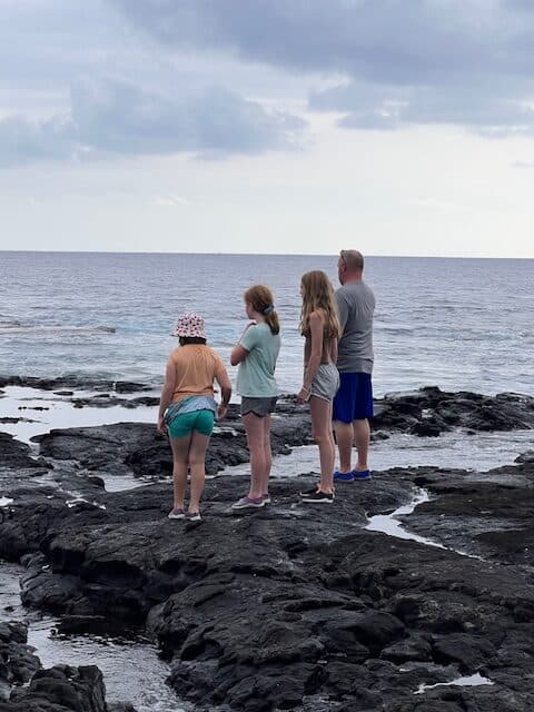 Kids wearing water shoes on the Lava Rocks on the Big Island of Hawaii. Water shoes are a good idea to pack for Hawaii. 