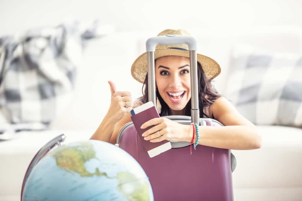 Happy woman shows thumbs up as travel restrictions ease and she can travel again, holding a passport and flight ticket.