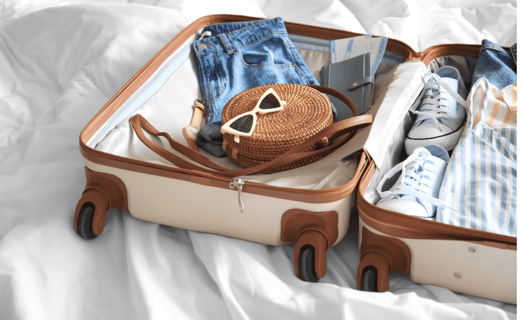 Suitcase filled with clothing items and sunglasses