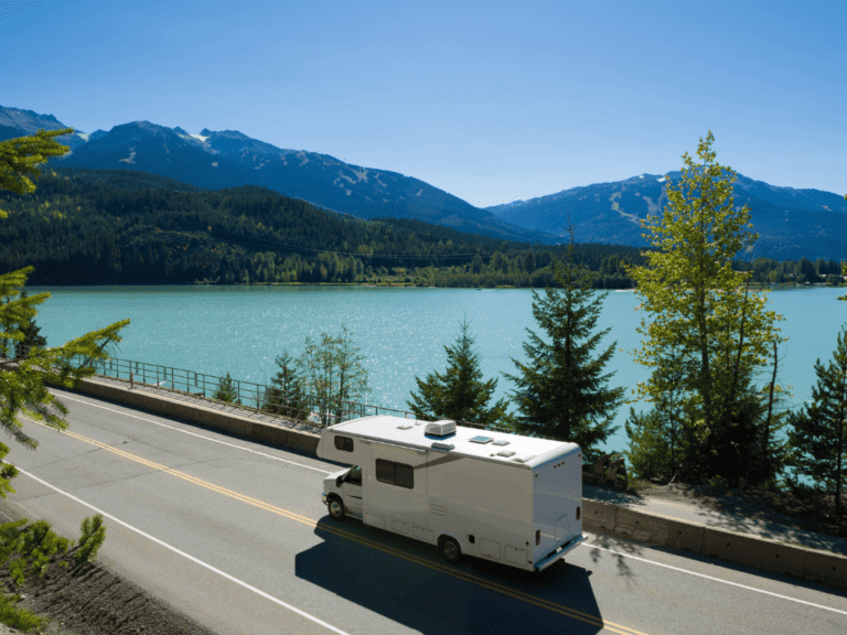 Camper driving along a lake in the mountains